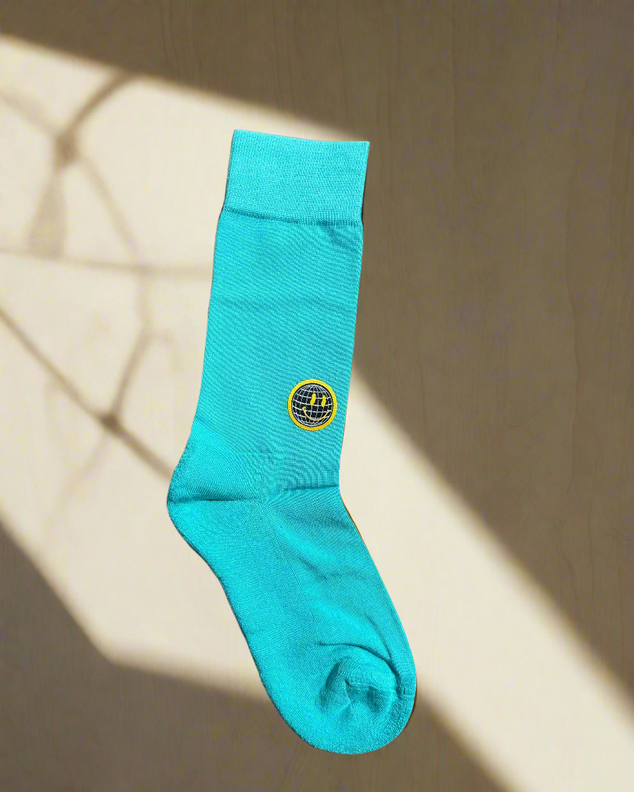 Turquoise sock with a yellow label on a beige background